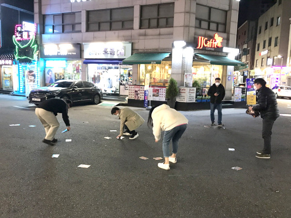 광진구 구의동 미가로 맛의 거리에 살포된 불법 유해전단지를 수거하고 있는 광진구청 직원들의 모습(4월)