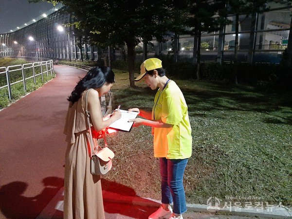 여성 안전귀가 대원이 반딧불이 서비스를 받고 있는 주민에게 서명을 받고 있다. / 서초구