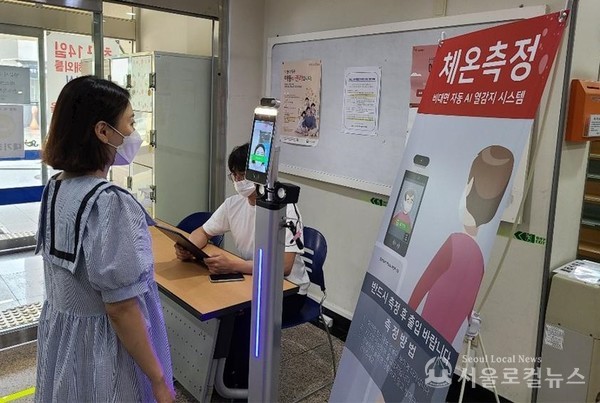 주민이 AI 안면인식 체온측정 카메라 앞에서 체온을 체크 마스크 착용 여부를 점검받고 있다.