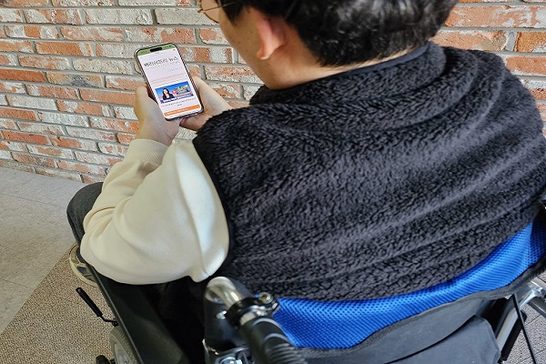 휴대폰으로 디지털 정보 신문을 보고 있는 장애인 구독자
