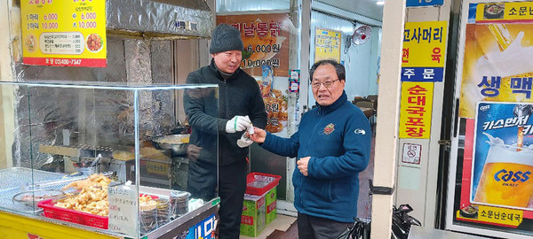 노룬산 골목시장 회장이 시장 상인들에게 구청에서 배부한 예방용품을 전달하고 있는 모습